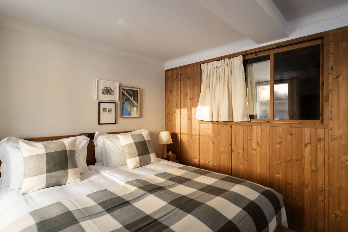 A Prestige room: wooden wall panels, a bed with a checked blanket and a window onto the garden