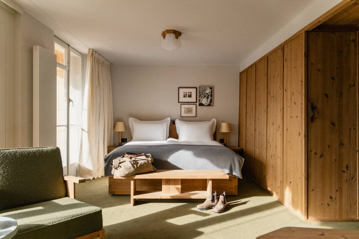 A Suite with a large bed, wood walls and wide windows