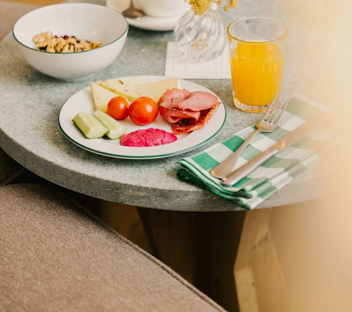 A breakfast plate with cheese, ham, tomatoes and juice