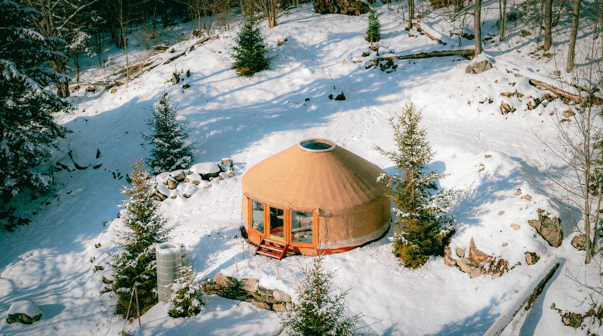 The round yoga yurt from above, in a snowy garden among fir trees